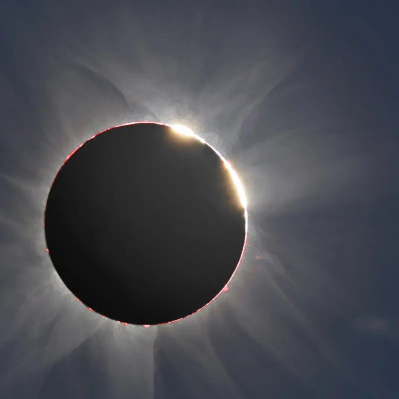 The dark Moon fringed by the corona, with two brilliant points of sunlight on its edge