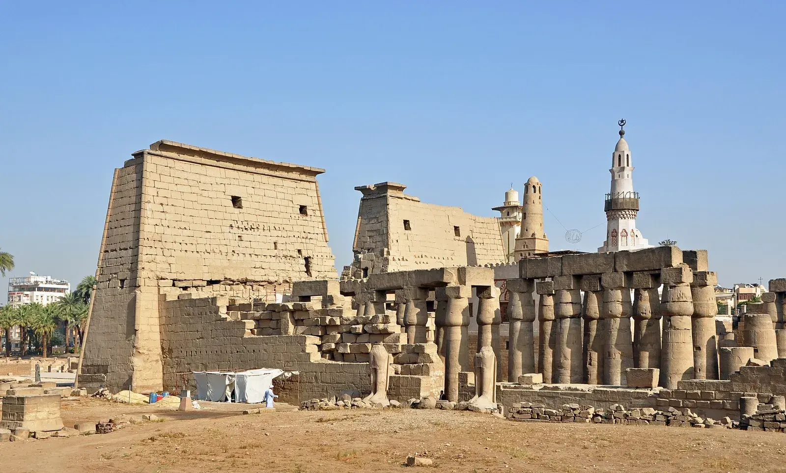 The great stone pylon and columns of Luxor Temple under a clear blue sky