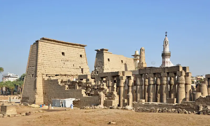 The great stone pylon and columns of Luxor Temple under a clear blue sky