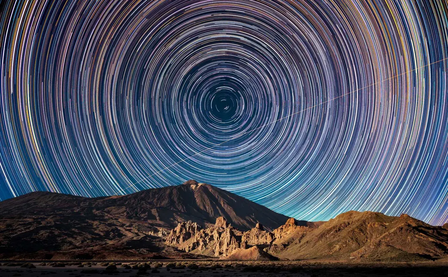 Circular star trails over the dark peak of Mount Teide and the rocks of the Cañadas crater